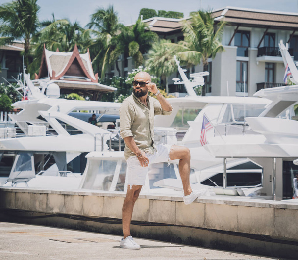 Portrait of a fashion young man posing at marina and yahts background - Φωτογραφία, εικόνα