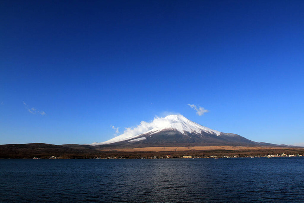 Montagne Fuji avec neige et brouillard couvert dessus, lac ou mer et fond ciel bleu clair avec espace de copie. Cet endroit célèbre au Japon et en Asie pour les gens voyagent pour visiter et prendre des photos. - Photo, image