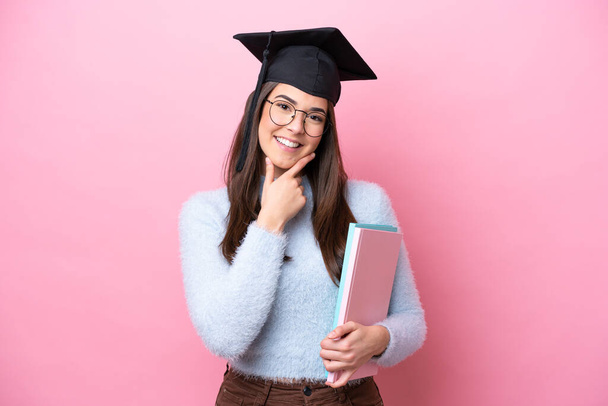 Jeune étudiante brésilienne portant un chapeau diplômé isolé sur fond rose heureux et souriant - Photo, image