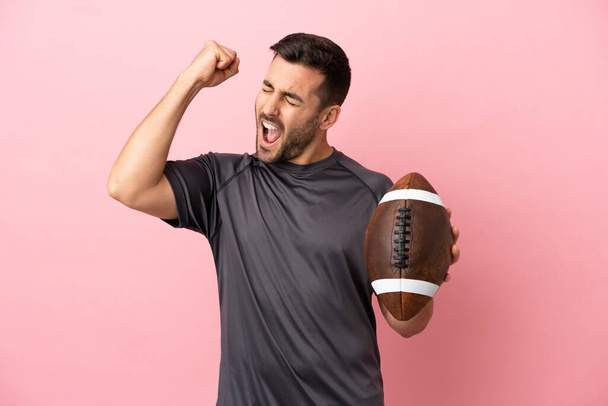 Young caucasian man playing rugby isolated on pink background celebrating a victory - Photo, Image