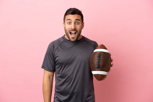Young caucasian man playing rugby isolated on pink background with surprise facial expression - Photo, Image
