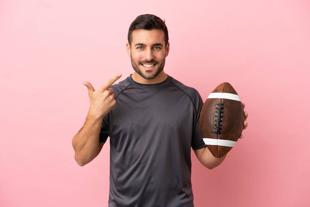 Young caucasian man playing rugby isolated on pink background giving a thumbs up gesture - Фото, изображение