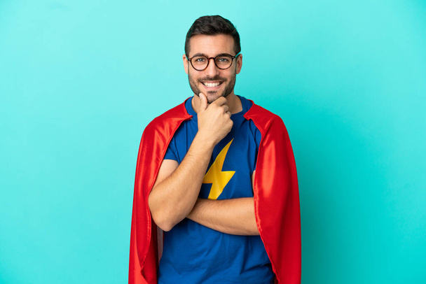 Super Hero caucasian man isolated on blue background with glasses and smiling - Fotografie, Obrázek