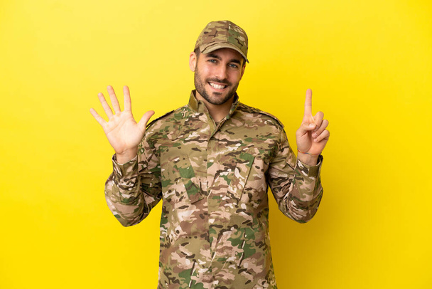 Military man isolated on yellow background counting six with fingers - 写真・画像