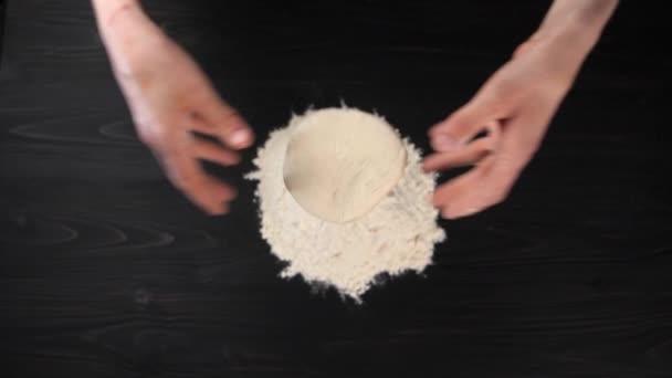Dłonie uwalniają ciasto, które wpada do mąki rozrzuconej na drewnianym stole. - Materiał filmowy, wideo