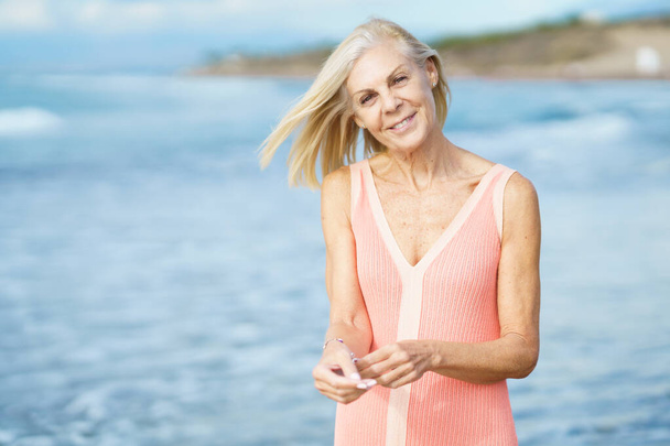 Mulher idosa desfrutando de sua aposentadoria em um retiro à beira-mar. Mulher sênior na costa de uma praia. - Foto, Imagem