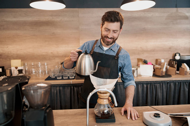 Sorrindo Barista derramando água para fazer café usando gotejamento manual cervejeiro - Foto, Imagem