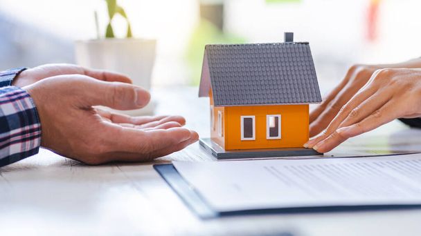 Immobilienmakler, der den Kunden zur Entscheidungsfindung präsentiert und berät, unterzeichnen Versicherungsformularvertrag, Hausmodell, betreffend Hypothekendarlehensangebot für und Hausversicherung. - Foto, Bild