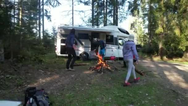 15 mei 2022 Babia Gora, Polen. RV Road Trip vakantie met vrienden. Twee blanke echtparen die rond het kampvuur hangen naast hun camper busje. Droge Kamperen in een bos. - Video