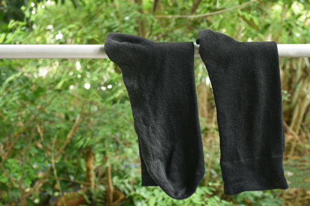  Arka bahçedeki kumaş ipinde kurutulduğu için asılmış eski siyah çorap. - Fotoğraf, Görsel