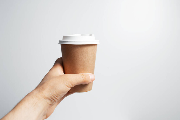 Close-up of male hand holding paper cup of coffee takeaway, on white background. - Photo, image