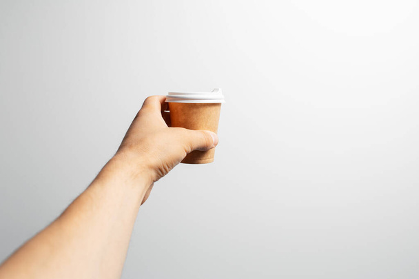 Gros plan de la main masculine tenant une petite tasse de café à emporter, sur blanc. - Photo, image