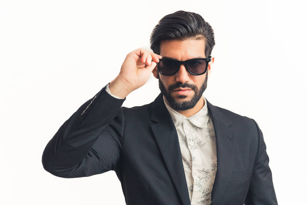 Portret van jonge zakenman zet zijn nieuwe zonnebril op witte achtergrond gesoldeerd horizontaal - Foto, afbeelding