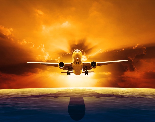 Jet passagiersvliegtuig vliegen over mooie zeeniveau met zonsondergang - Foto, afbeelding