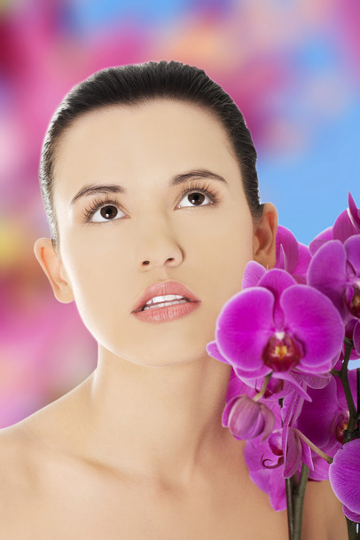 Beautiful woman with an orchid flower - Фото, изображение
