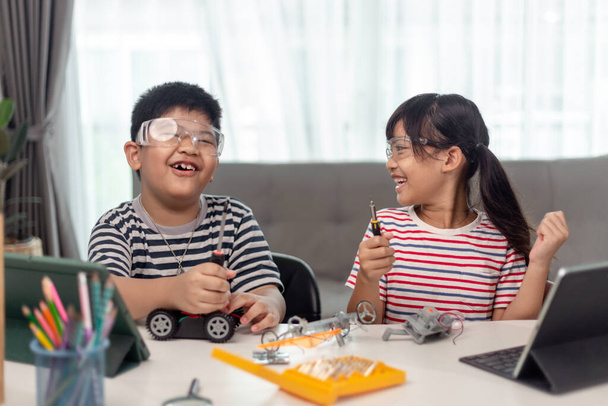 zwei asiatische Kinder, die Spaß am gemeinsamen Programmieren haben, zu Hause fernlernen, MINT-Wissenschaft, Hausaufgabenbetreuung, soziale Distanzierung, Isolation, neues normales Konzept - Foto, Bild