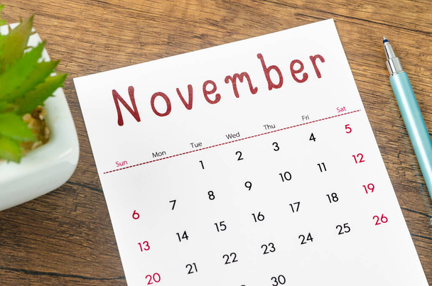 The November 2022 calendar and pen on wooden background. - Foto, Bild
