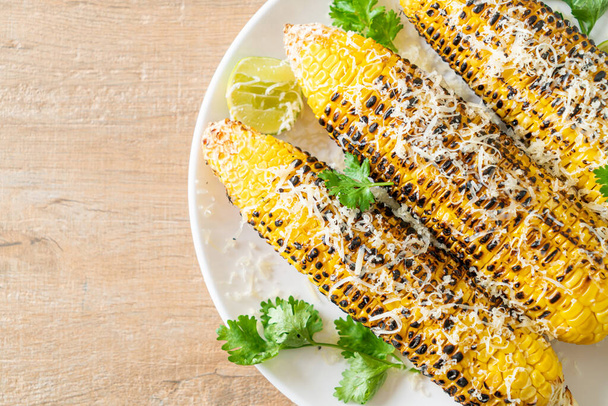 барбекю и жареная кукуруза с сыром и лаймом на тарелке - Фото, изображение