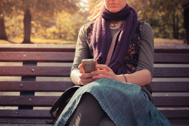 Young woman on park bench using her phone - Фото, зображення
