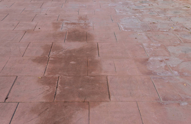 Вагонка бетонна підлога зовнішня тротуарна плитка зношена, зовнішній вигляд натурального каменю, імітує кольори і текстури матеріалів тротуарів, червоний квадратний візерунок мокрий і вологий
 - Фото, зображення