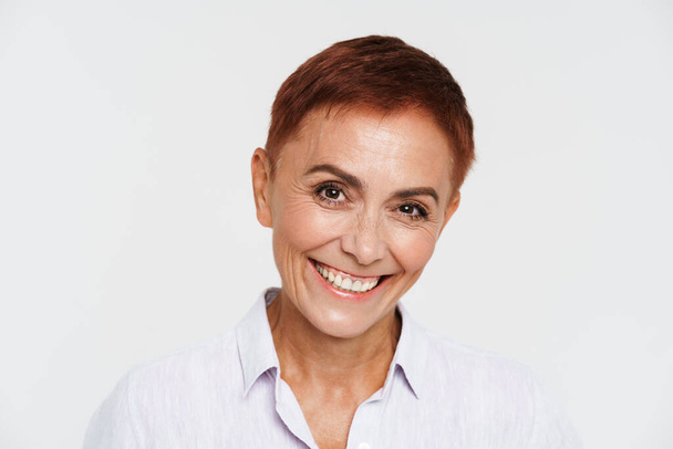 Ginger senior woman with short hair smiling and looking at camera isolated over white background - Foto, Imagem