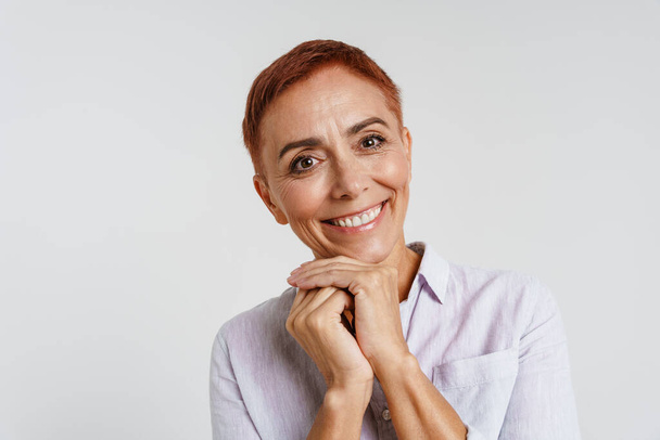 Ginger senior woman with short hair smiling and looking at camera isolated over white background - Fotografie, Obrázek