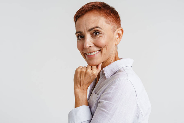 Ginger senior woman with short hair smiling and looking at camera isolated over white background - Fotoğraf, Görsel