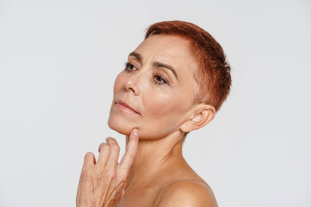 Senior shirtless woman with short hair posing and looking aside isolated over white background - Foto, afbeelding