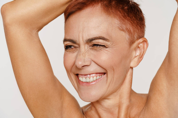 Senior shirtless woman with short hair smiling and winking isolated over white background - Photo, Image