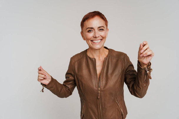 Ginger senior woman with short hair smiling and dancing isolated over white background - Φωτογραφία, εικόνα