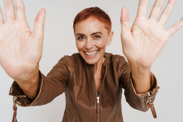 Ginger senior woman with short hair smiling and showing her palms isolated over white background - Фото, зображення