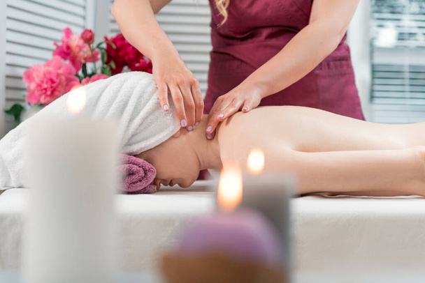 Kobieta korzystająca relaksujący masaż pleców w centrum spa kosmetologii. Masażysta robi masaż szyi - Zdjęcie, obraz