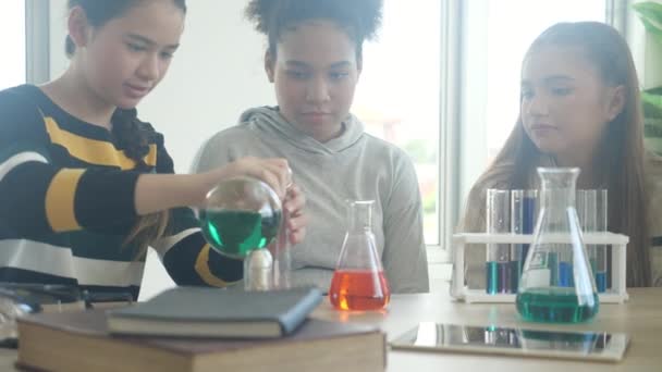 Fiatal tanár tanítási csoport hallgató a tudományról és elmagyarázza kémiai folyadék az iskolai laborban, a gyermekek tanul és tanul kísérletezés tudomány a laboratóriumban, oktatási koncepció. - Felvétel, videó
