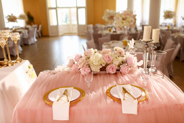 прикраса столу рожевою скатертиною, кришталевими свічками зі свічками та білими рожевими квітами в ресторані. стильний день весілля. встановлення столу з золотою тарілкою, виделкою та ножем
. - Фото, зображення