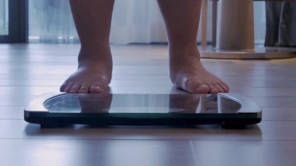 zicht op de vloer terwijl een man in close-up op digitale smart scales staat - Video
