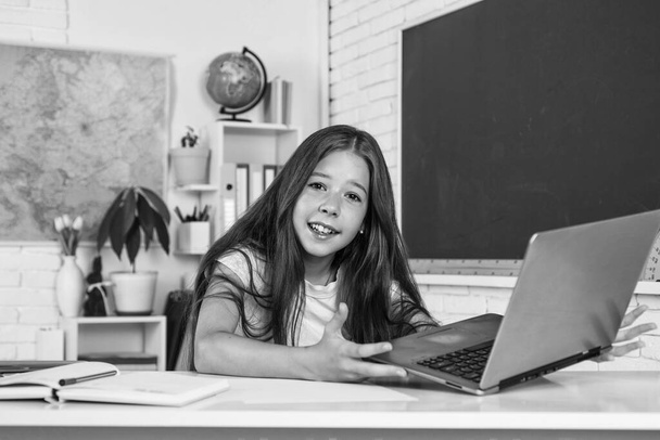 Cute teen child near chalkboard with laptop on online lesson, back to school - Valokuva, kuva