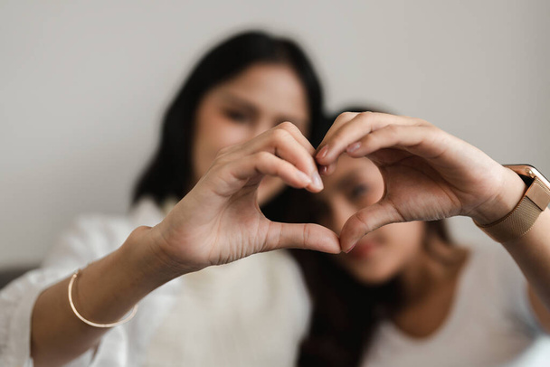 Lesbian lifestyle girlfriends doing heart shape symbol with hands - Фото, изображение