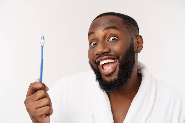 portrait of a happy young dark-anm brushing his teeth with black toothpaste on a white background. - Zdjęcie, obraz