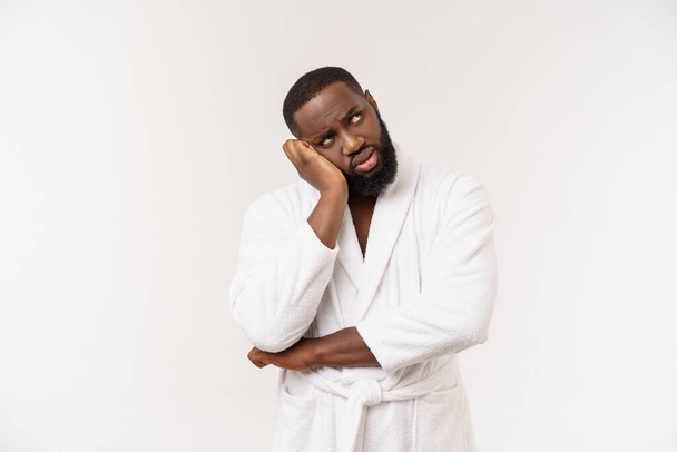 Jovem afro-americano vestindo roupão de banho sobre fundo branco isolado pensando cansado e entediado com problemas de depressão
. - Foto, Imagem