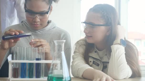 Genç öğretmen grup öğrencilerine bilim öğretiyor ve okul laboratuvarında sıvı için kimyasalı açıklıyordu, çocuklar laboratuarda deney bilimi okuyor ve öğreniyor, eğitim konsepti. - Video, Çekim