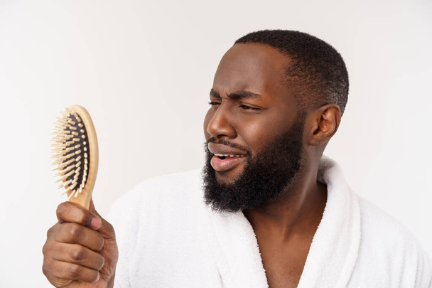Portrait of handsome young african american man combing his hair in bathroom. Isolated over white background - 写真・画像