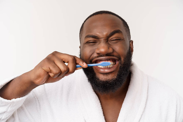 ritratto di un giovane felice anm scuro che si lava i denti con dentifricio nero su sfondo bianco
. - Foto, immagini