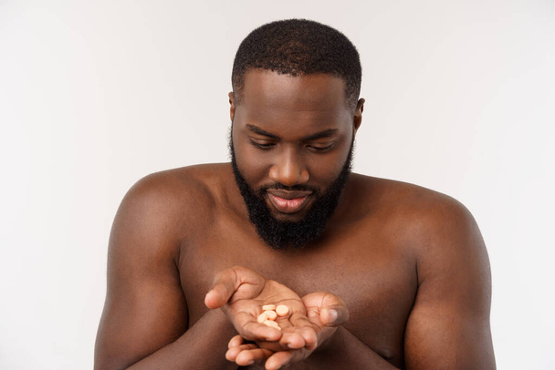 Kranker Afroamerikaner isst Medikamentenpille Schwarzer Mann steht auf schlichtem Hintergrund mit Kopierraum. - Foto, Bild