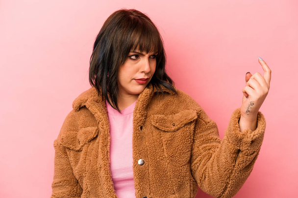 Young caucasian woman isolated on pink background pointing with finger at you as if inviting come closer. - Photo, Image