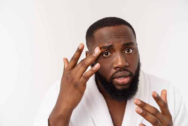 O homem afro-americano olha para espinhas na cara. Acne. A higiene masculina. Isolado em fundo branco. Retrato de estúdio - Foto, Imagem