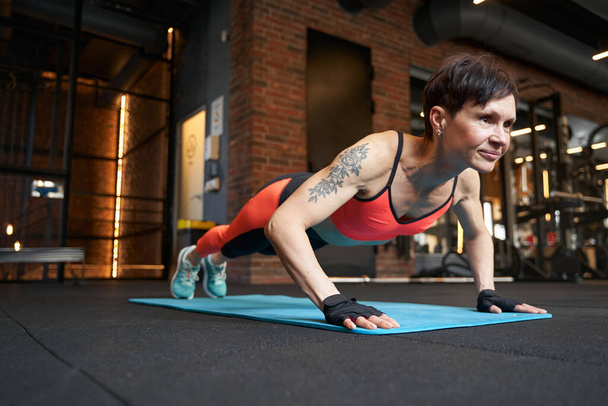 Sporty lady doing press-ups in fitness club - Foto, afbeelding