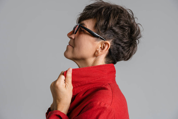 Mature european woman wearing sunglasses looking aside isolated over grey background - Foto, Bild
