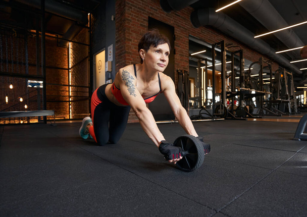 Professional female athlete performing ab wheel rollout - 写真・画像
