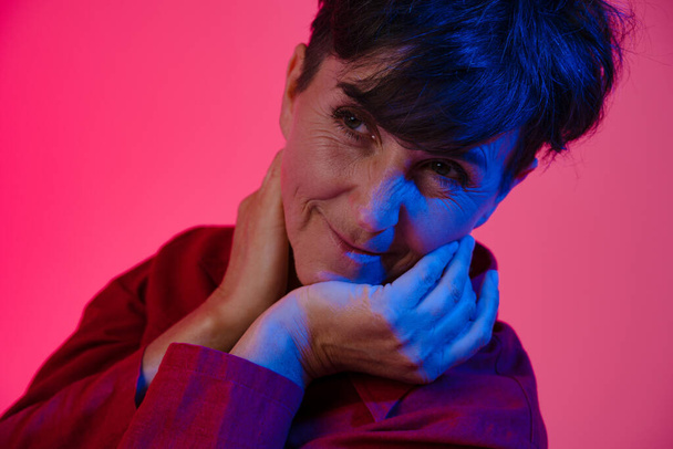 Mature european woman wearing shirt smiling and looking aside isolated over pink background - Φωτογραφία, εικόνα