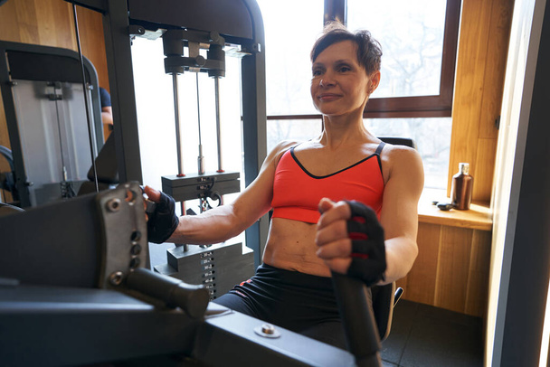 Muscular sportswoman working out in fitness club - Φωτογραφία, εικόνα